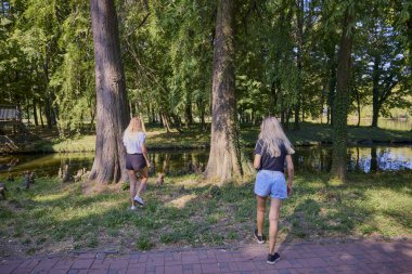 İki orta yaşlı kız kardeş bir yaz sabahını parkta dinlenerek ve eğlenerek geçiriyorlar..