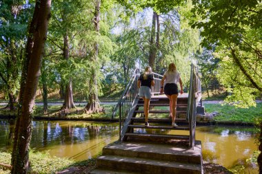İki orta yaşlı kız kardeş bir yaz sabahını parkta dinlenerek ve eğlenerek geçiriyorlar..