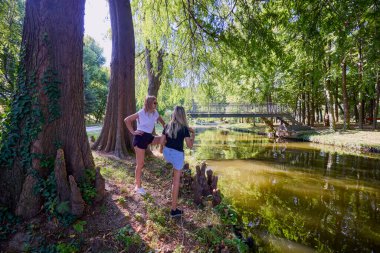 İki orta yaşlı kız kardeş bir yaz sabahını parkta dinlenerek ve eğlenerek geçiriyorlar..