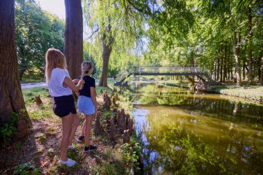 İki orta yaşlı kız kardeş bir yaz sabahını parkta dinlenerek ve eğlenerek geçiriyorlar..