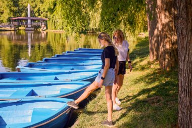 İki orta yaşlı kız kardeş bir yaz sabahını parkta dinlenerek ve eğlenerek geçiriyorlar..