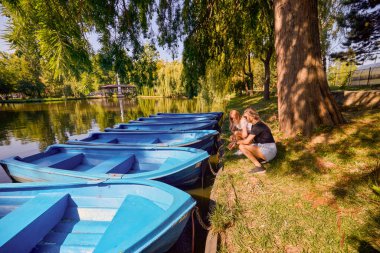 İki orta yaşlı kız kardeş bir yaz sabahını parkta dinlenerek ve eğlenerek geçiriyorlar..