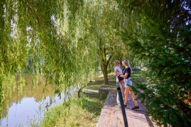 İki orta yaşlı kız kardeş bir yaz sabahını parkta dinlenerek ve eğlenerek geçiriyorlar..