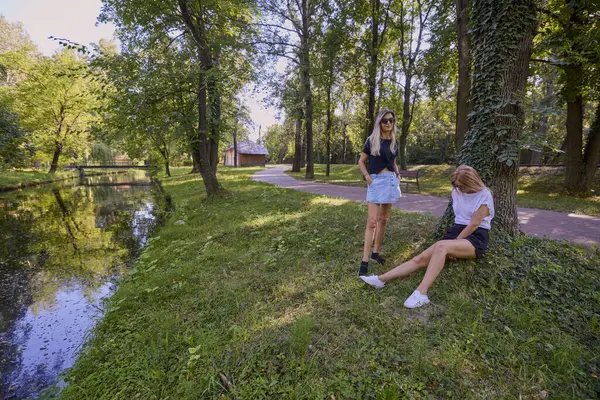 İki orta yaşlı kız kardeş bir yaz sabahını parkta dinlenerek ve eğlenerek geçiriyorlar..