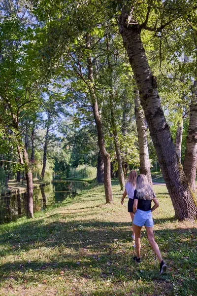 İki orta yaşlı kız kardeş bir yaz sabahını parkta dinlenerek ve eğlenerek geçiriyorlar..