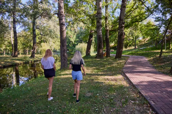 İki orta yaşlı kız kardeş bir yaz sabahını parkta dinlenerek ve eğlenerek geçiriyorlar..
