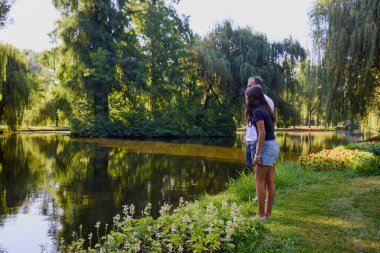 Baba ve kızı bir yaz sabahı göl kenarında parkta birlikte vakit geçiriyorlar doğanın tadını çıkarıyorlar..