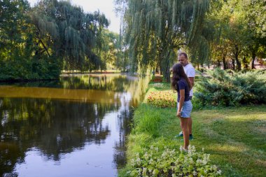 Baba ve kızı bir yaz sabahı göl kenarında parkta birlikte vakit geçiriyorlar doğanın tadını çıkarıyorlar..