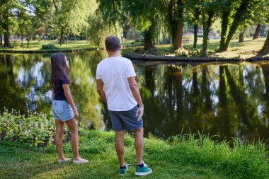 Baba ve kızı bir yaz sabahı göl kenarında parkta birlikte vakit geçiriyorlar doğanın tadını çıkarıyorlar..