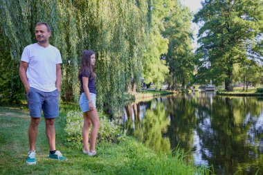 Baba ve kızı bir yaz sabahı göl kenarında parkta birlikte vakit geçiriyorlar doğanın tadını çıkarıyorlar..