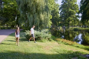 Baba ve kızı bir yaz sabahı göl kenarında parkta birlikte vakit geçiriyorlar doğanın tadını çıkarıyorlar..