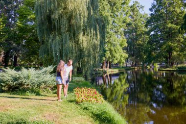 Baba ve kızı bir yaz sabahı göl kenarında parkta birlikte vakit geçiriyorlar doğanın tadını çıkarıyorlar..