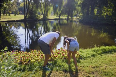 Baba ve kızı bir yaz sabahı göl kenarında parkta birlikte vakit geçiriyorlar doğanın tadını çıkarıyorlar..