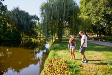 Baba ve kızı bir yaz sabahı göl kenarında parkta birlikte vakit geçiriyorlar doğanın tadını çıkarıyorlar..