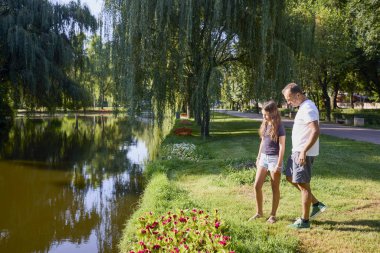 Baba ve kızı bir yaz sabahı göl kenarında parkta birlikte vakit geçiriyorlar doğanın tadını çıkarıyorlar..