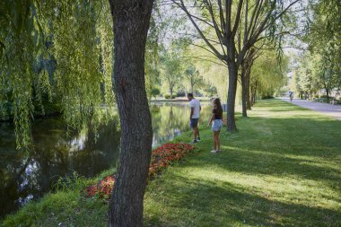Baba ve kızı bir yaz sabahı göl kenarında parkta birlikte vakit geçiriyorlar doğanın tadını çıkarıyorlar..