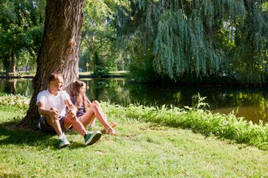 Baba ve kızı bir yaz sabahı göl kenarında parkta birlikte vakit geçiriyorlar doğanın tadını çıkarıyorlar..