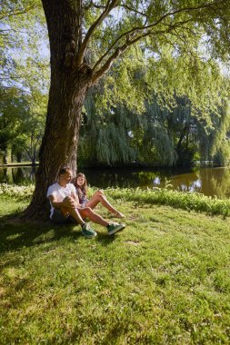 Baba ve kızı bir yaz sabahı göl kenarında parkta birlikte vakit geçiriyorlar doğanın tadını çıkarıyorlar..
