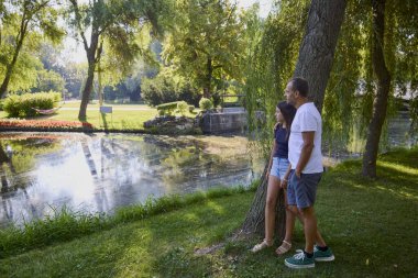 Baba ve kızı bir yaz sabahı göl kenarında parkta birlikte vakit geçiriyorlar doğanın tadını çıkarıyorlar..