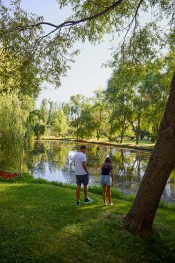 Baba ve kızı bir yaz sabahı göl kenarında parkta birlikte vakit geçiriyorlar doğanın tadını çıkarıyorlar..