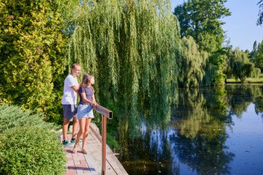 Baba ve kızı bir yaz sabahı göl kenarında parkta birlikte vakit geçiriyorlar doğanın tadını çıkarıyorlar..