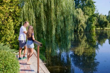 Baba ve kızı bir yaz sabahı göl kenarında parkta birlikte vakit geçiriyorlar doğanın tadını çıkarıyorlar..