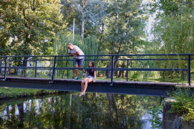 Baba ve kızı bir yaz sabahı göl kenarında parkta birlikte vakit geçiriyorlar doğanın tadını çıkarıyorlar..