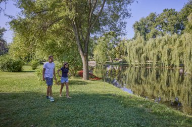 Baba ve kızı bir yaz sabahı göl kenarında parkta birlikte vakit geçiriyorlar doğanın tadını çıkarıyorlar..