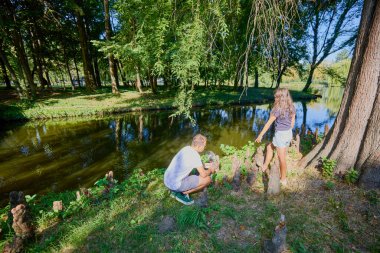 Baba ve kızı bir yaz sabahı göl kenarında parkta birlikte vakit geçiriyorlar doğanın tadını çıkarıyorlar..