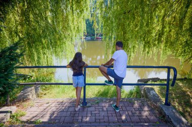Baba ve kızı bir yaz sabahı göl kenarında parkta birlikte vakit geçiriyorlar doğanın tadını çıkarıyorlar..