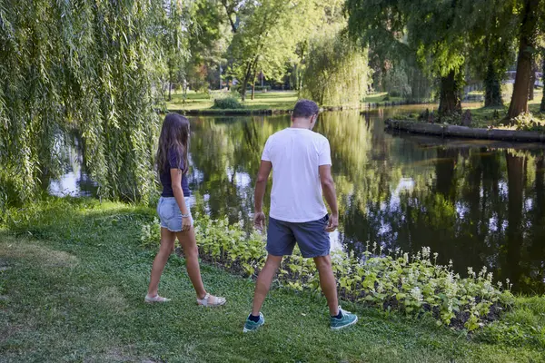 Baba ve kızı bir yaz sabahı göl kenarında parkta birlikte vakit geçiriyorlar doğanın tadını çıkarıyorlar..