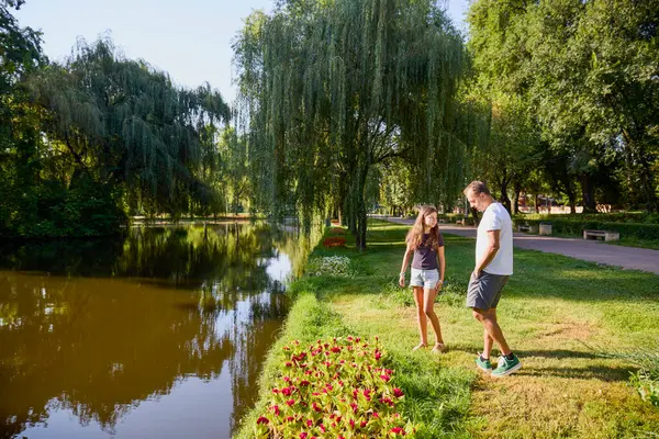 Baba ve kızı bir yaz sabahı göl kenarında parkta birlikte vakit geçiriyorlar doğanın tadını çıkarıyorlar..