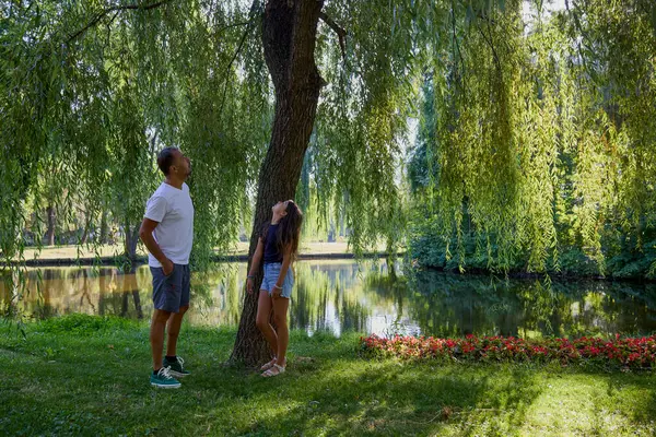 Baba ve kızı bir yaz sabahı göl kenarında parkta birlikte vakit geçiriyorlar doğanın tadını çıkarıyorlar..