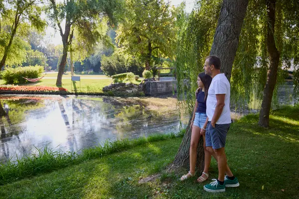 Baba ve kızı bir yaz sabahı göl kenarında parkta birlikte vakit geçiriyorlar doğanın tadını çıkarıyorlar..