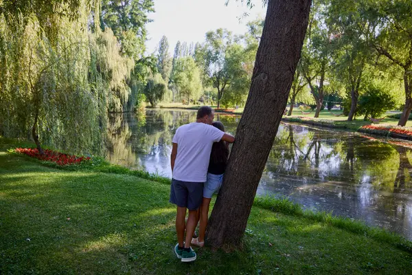 Baba ve kızı bir yaz sabahı göl kenarında parkta birlikte vakit geçiriyorlar doğanın tadını çıkarıyorlar..