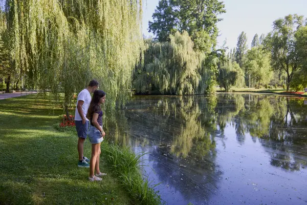 Baba ve kızı bir yaz sabahı göl kenarında parkta birlikte vakit geçiriyorlar doğanın tadını çıkarıyorlar..
