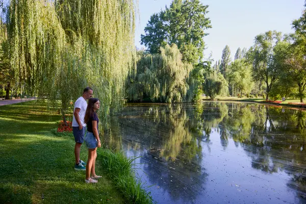 Baba ve kızı bir yaz sabahı göl kenarında parkta birlikte vakit geçiriyorlar doğanın tadını çıkarıyorlar..