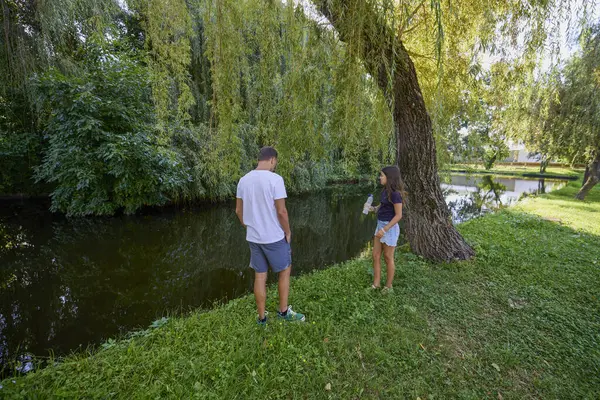 Baba ve kızı bir yaz sabahı göl kenarında parkta birlikte vakit geçiriyorlar doğanın tadını çıkarıyorlar..