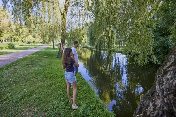 Baba ve kızı bir yaz sabahı göl kenarında parkta birlikte vakit geçiriyorlar doğanın tadını çıkarıyorlar..