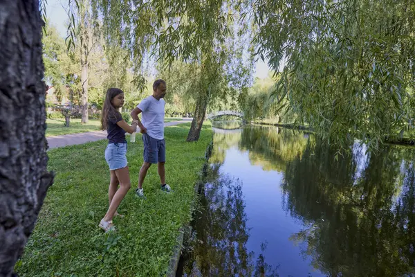 Baba ve kızı bir yaz sabahı göl kenarında parkta birlikte vakit geçiriyorlar doğanın tadını çıkarıyorlar..