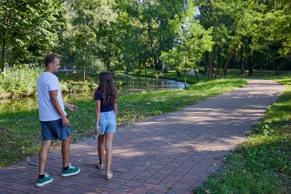 Baba ve kızı bir yaz sabahı göl kenarında parkta birlikte vakit geçiriyorlar doğanın tadını çıkarıyorlar..