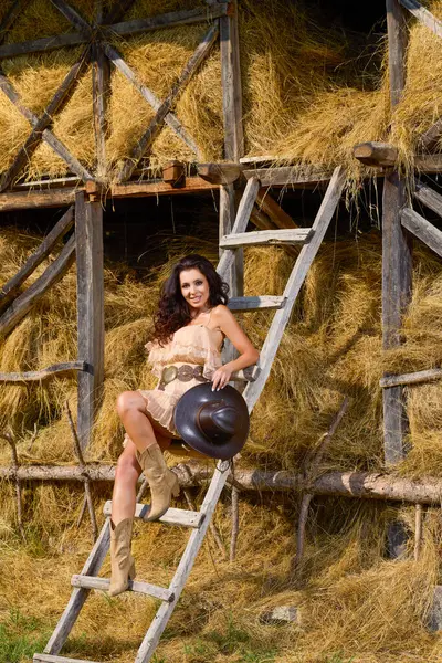 Güzel bir kadının portresi. Kır kıyafetleri içinde, saman ambarının yanında.