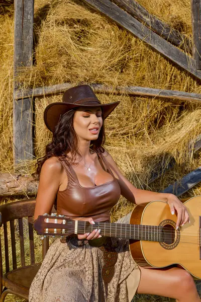 Kır kıyafetleri içinde güzel bir kadın ve saman ambarının yanında şapka, köy konsepti..