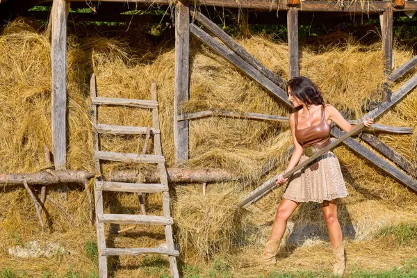 Kır kıyafetleri içinde güzel bir kadın ve saman ambarının yanında şapka, köy konsepti..
