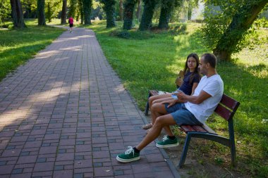 Baba ve kızı parkta birlikte zaman geçiriyorlar. Egzersiz yapıyor ve dinleniyorlar..