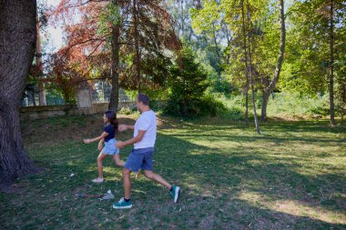 Baba ve kızı parkta birlikte zaman geçiriyorlar. Egzersiz yapıyor ve dinleniyorlar..