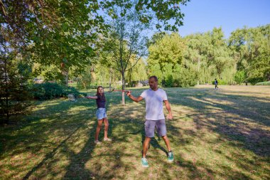 Baba ve kızı parkta birlikte zaman geçiriyorlar. Egzersiz yapıyor ve dinleniyorlar..