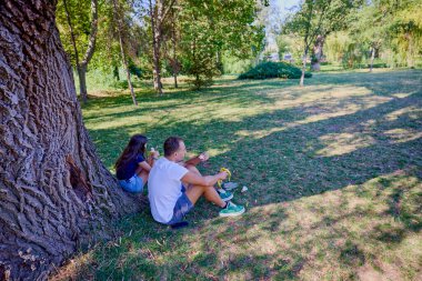 Baba ve kızı parkta birlikte zaman geçiriyorlar. Egzersiz yapıyor ve dinleniyorlar..