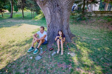 Baba ve kızı parkta birlikte zaman geçiriyorlar. Egzersiz yapıyor ve dinleniyorlar..