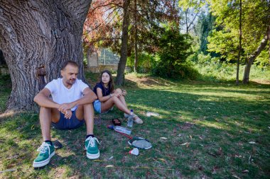 Baba ve kızı parkta birlikte zaman geçiriyorlar. Egzersiz yapıyor ve dinleniyorlar..